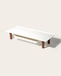 The Gather Small Monitor Stand (White/Walnut) features a minimalist white top with rounded corners, four cylindrical walnut legs, and a slanted lower shelf—ideal as a space-saving desk organizer.
