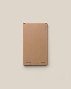 A plain brown cardboard box with “Analog” on the lower left and “Someday” on the lower right holds the Analog - Someday Cards (1-Pack), ideal for storing your planning cards, set against a light beige background.