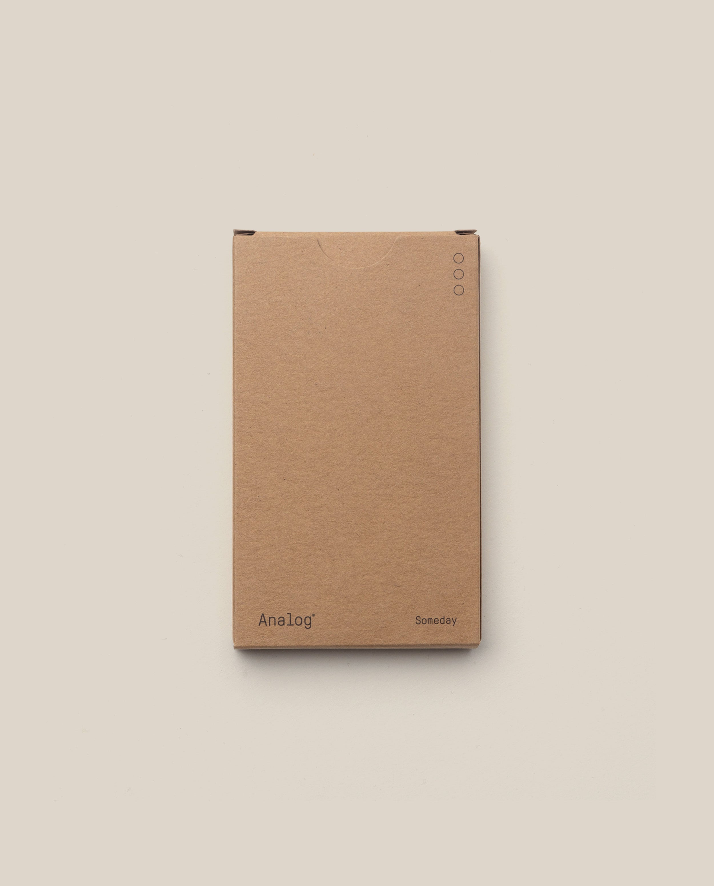 A plain brown cardboard box with “Analog” on the lower left and “Someday” on the lower right holds the Analog - Someday Cards (1-Pack), ideal for storing your planning cards, set against a light beige background.