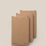 Three brown cardboard boxes of Analog - Someday Cards (3-Pack) are stacked in a staggered arrangement on a light beige background, featuring uncoated writing cards for versatile organization.