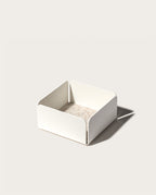 The Gather 2x2 Organizer Set (White) is a minimalist, powder-coated steel organizer with a square shape, rounded corners, and low sides. It features a light beige base and casts a right-side shadow on a plain background.