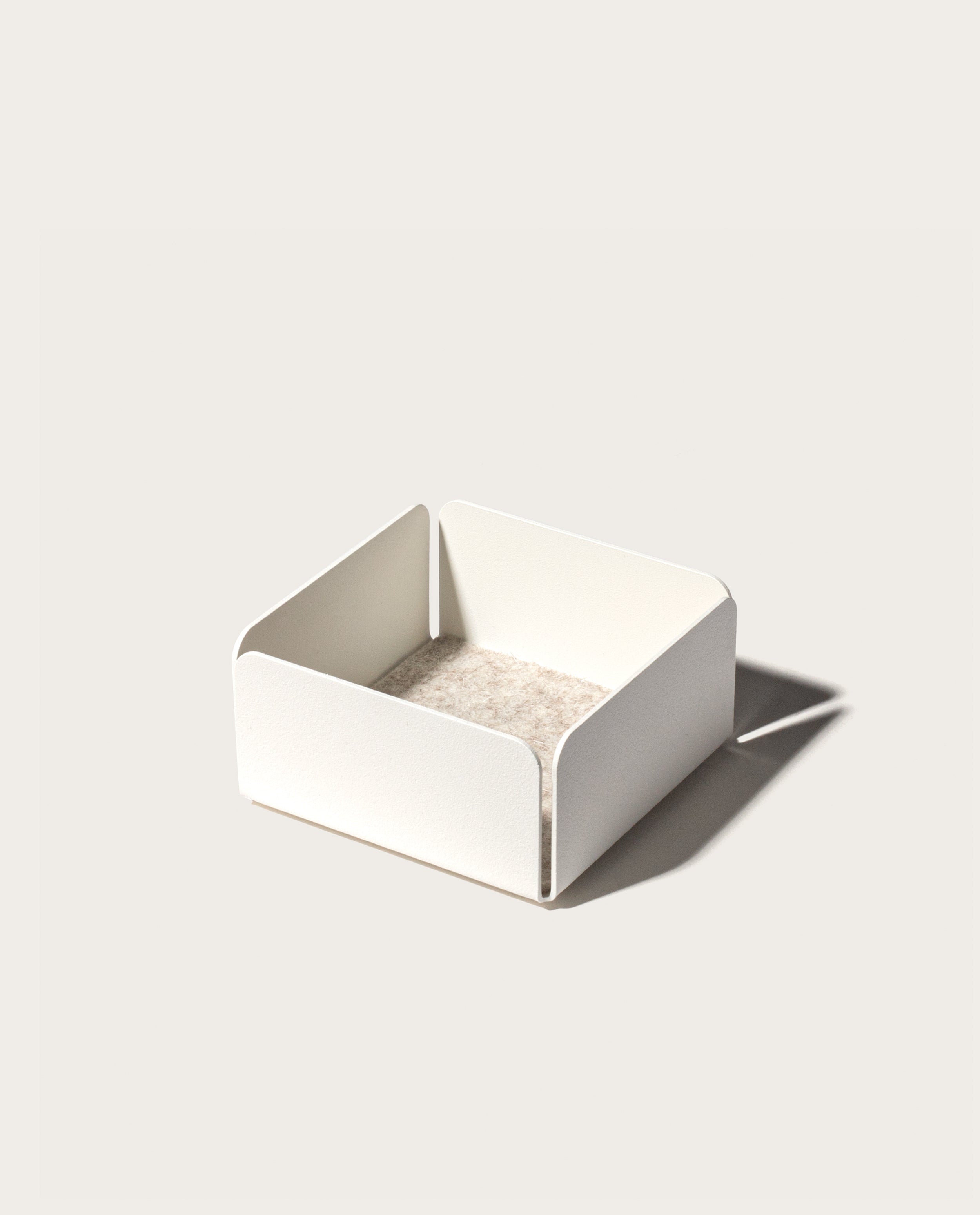 The Gather 2x2 Organizer Set (White) is a minimalist, powder-coated steel organizer with a square shape, rounded corners, and low sides. It features a light beige base and casts a right-side shadow on a plain background.