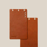 Two brown leather notebooks with 'Analog' branding on a beige background