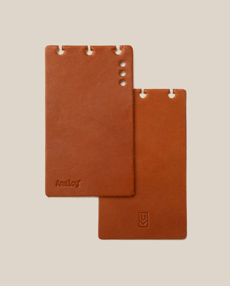 Two brown leather notebooks with 'Analog' branding on a beige background