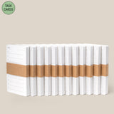 A diagonal row of Analog - Task Cards (12-Pack) notepads, each stacked and wrapped with brown paper bands, is displayed on a beige background. A green circle in the top left highlights them as ideal for analog productivity system fans.