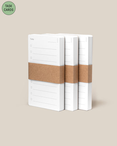 Three stacks of Analog - Task Cards (3-Pack), each bound with a brown paper band, are displayed on a beige background. A green circle in the top left highlights them as an analog productivity system called TASK CARDS.