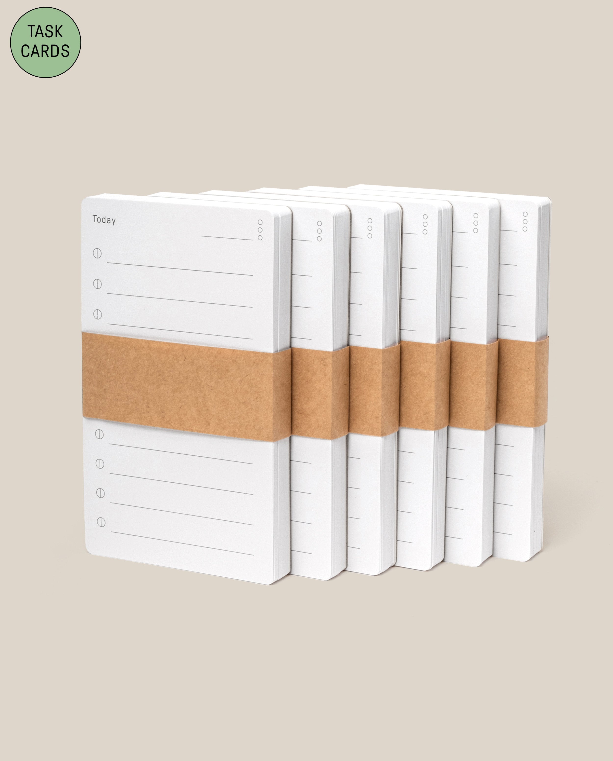 Six stacks of Analog - Task Cards (6-Pack), each with "Today" and lines printed, wrapped in brown paper bands, are arranged in a row on a beige background. A green circle in the corner displays "Task Cards.