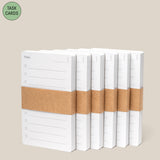 Six stacks of Analog - Task Cards (6-Pack), each with "Today" and lines printed, wrapped in brown paper bands, are arranged in a row on a beige background. A green circle in the corner displays "Task Cards.
