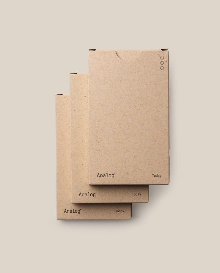 Three stacked brown cardboard boxes of the Analog - Today Cards (3-Pack) sit against a plain beige background, with “Analog” and “Today” on the lower corners and minimalist circle details in the upper right.