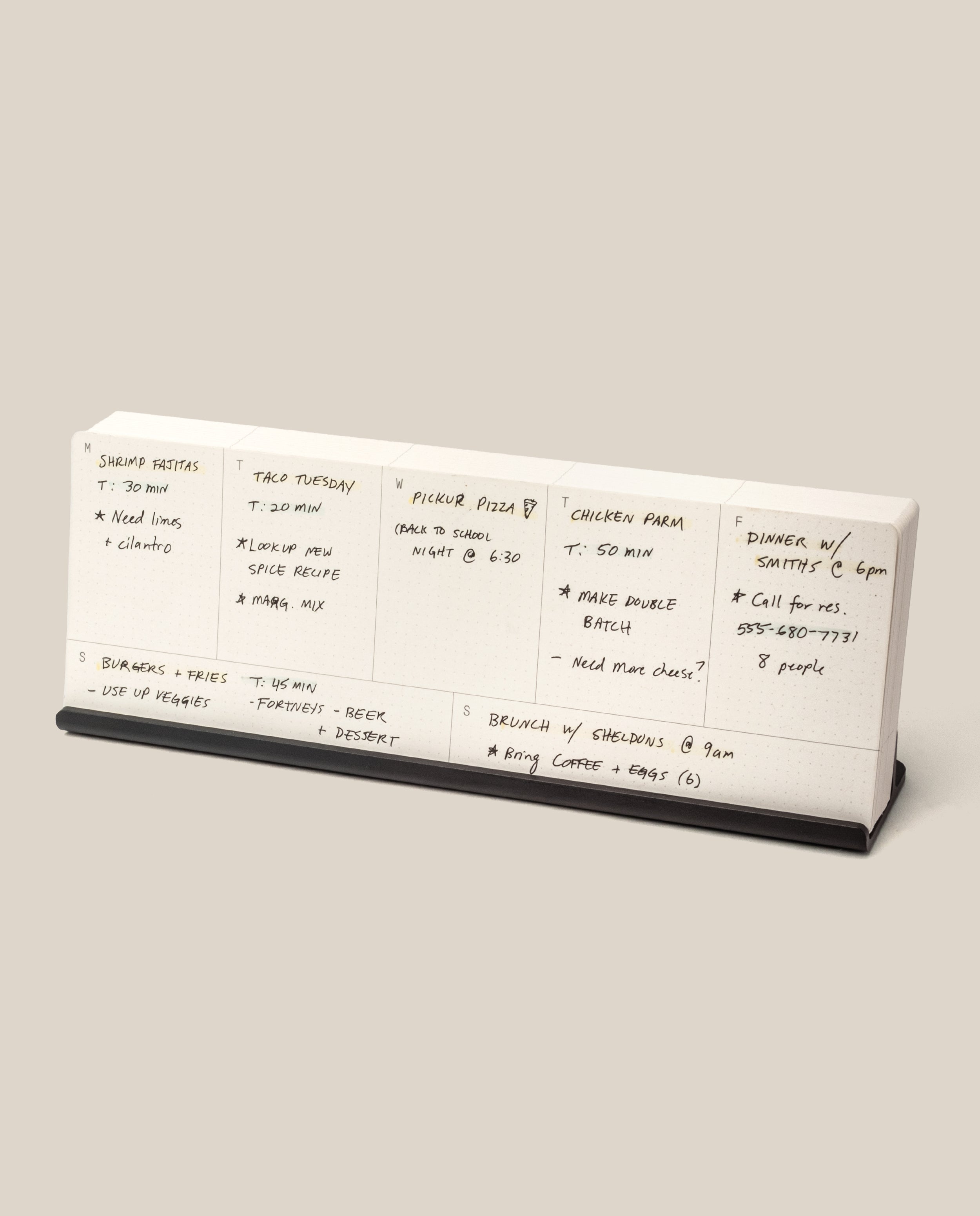 The Analog Weekly Planning Kit (Black Aluminum) is a desktop planner with seven sections for each day, labeled for meal ideas, ingredients, cooking times, and notes. It features a sleek black aluminum base for stylish organization.