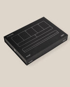 A black rectangular box with white line illustrations and "UGMONK" and "Analog" on the lid, featuring the Analog Weekly Planning Kit (Silver Aluminum), is placed on a plain beige background.