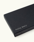 A rectangular black box for the Analog Premium Weekly Kit (Maple), designed to store Weekly Planner Cards, displays "Analog Weekly" in white on the lid and ugmonk.com/analog on the side, set against a plain white background.