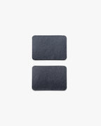 Two rectangular, dark gray slate pieces with rounded corners from the Magnet Kit (Pen Tray and Analog Weekly) are placed vertically on a plain white background, spaced evenly apart—these streamlined accessories are designed to complement your Gather Monitor Stand or Pen Tray. Cleverly integrated magnets help keep these sleek pieces securely in place on your workspace.