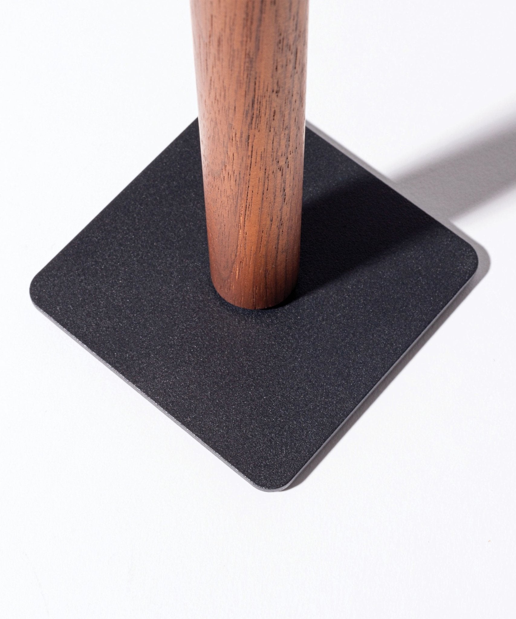 The Gather Headphone Stand (1x1 - Black/Walnut) features a solid walnut cylindrical pole set into a flat, black powder-coated steel square base, creating a minimalist look against a bright white background.