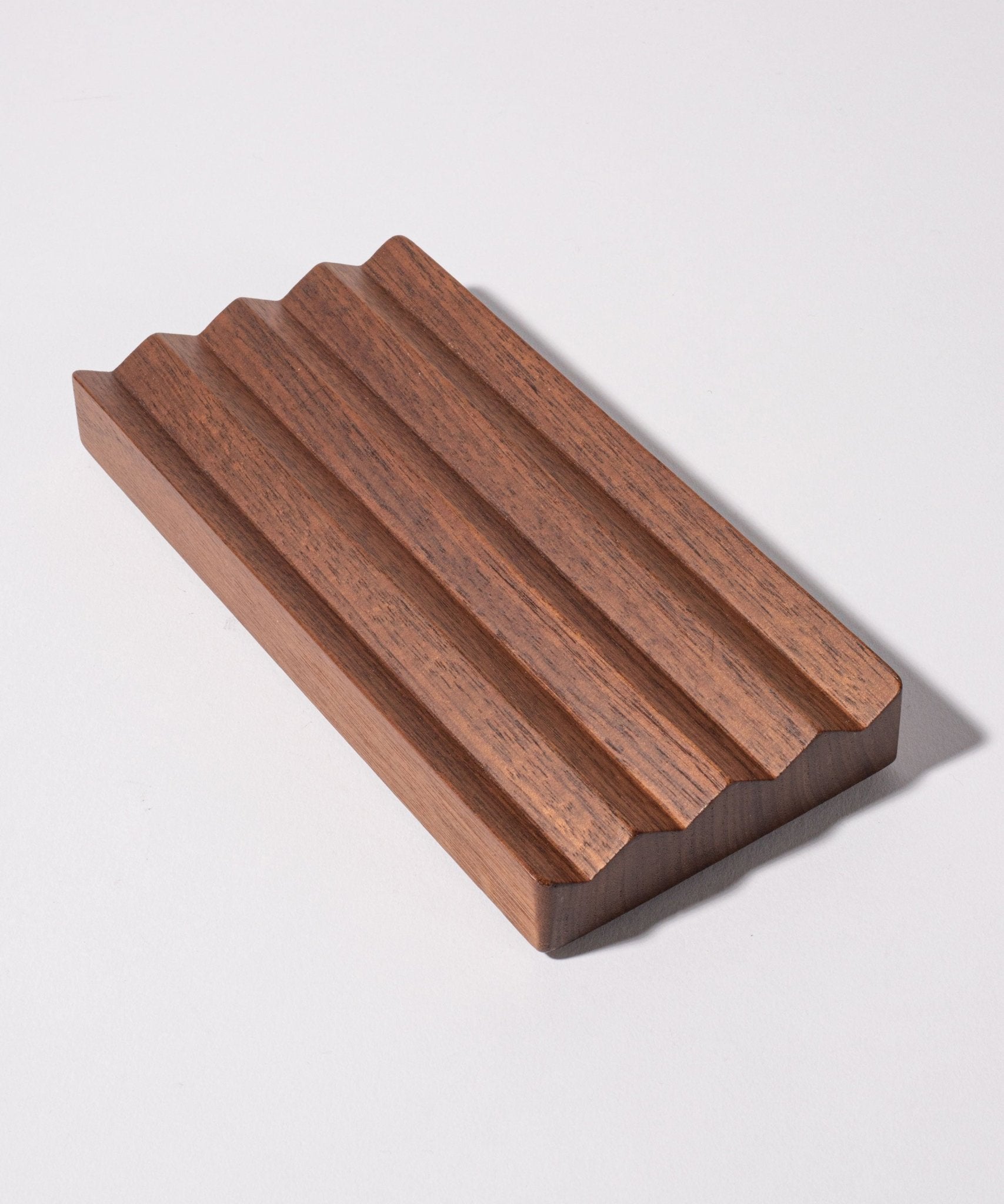 The Gather Wood Zigzag Tray (2x1 - Walnut) is crafted from solid walnut and features a unique zigzag design, making it a stylish holder for pens and pencils.