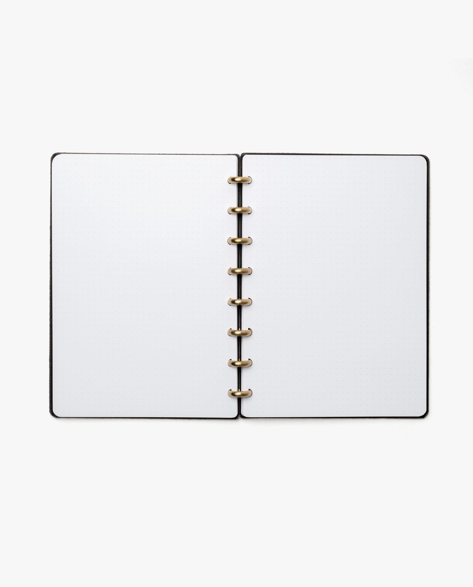The Discbound Heirloom Journal (Black Leather - Standard 6" x 8.5") features blank white pages and gold rings, lying open on a white background.