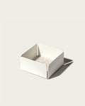 The Gather Small Tray (1x1 - White) features a minimalist white square design with open sides, rounded corners, and a beige interior. Made in Pennsylvania, it’s ideal as a desk organizer and casts a right-side shadow on light surfaces.