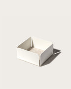 The Gather Small Tray (1x1 - White) features a minimalist white square design with open sides, rounded corners, and a beige interior. Made in Pennsylvania, it’s ideal as a desk organizer and casts a right-side shadow on light surfaces.