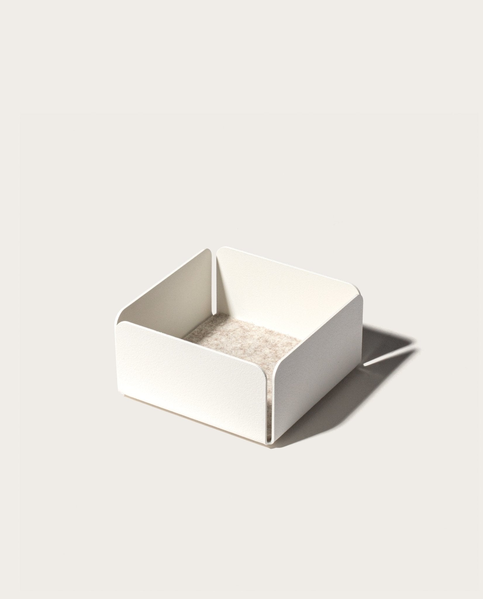 The Gather Small Tray (1x1 - White) features a minimalist white square design with open sides, rounded corners, and a beige interior. Made in Pennsylvania, it’s ideal as a desk organizer and casts a right-side shadow on light surfaces.
